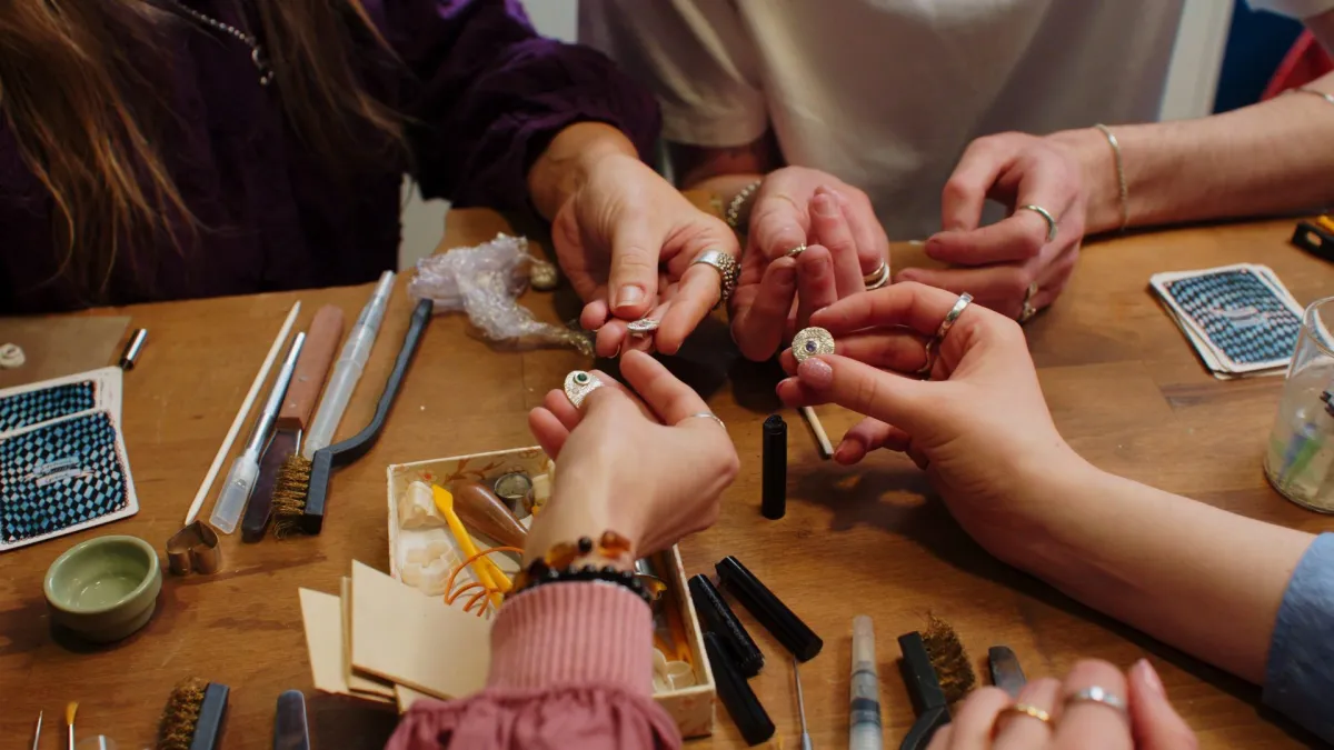 People crafting jewelry at a table.