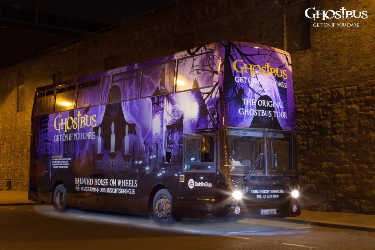 Purple-themed ghost tour bus at night.