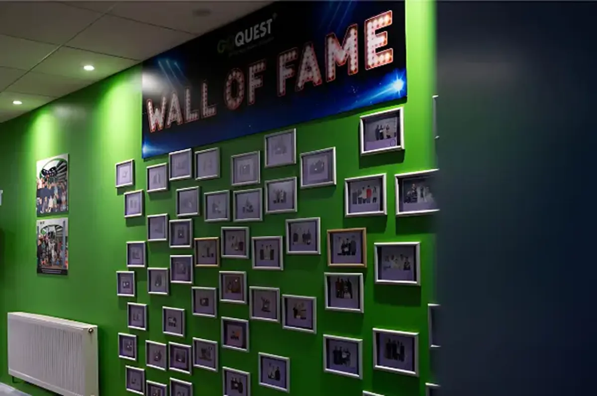 Wall of Fame with framed photos on a green wall.