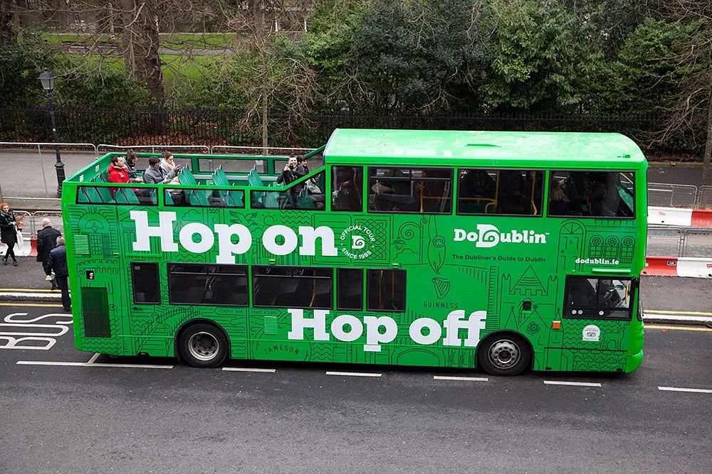 Green double-decker tour bus with 'Hop on Hop off' text