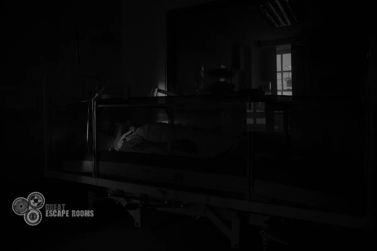 Dimly lit hospital room with a bed and window.