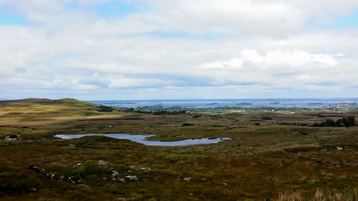 Scenic landscape with hills and a lake under cloudy sky