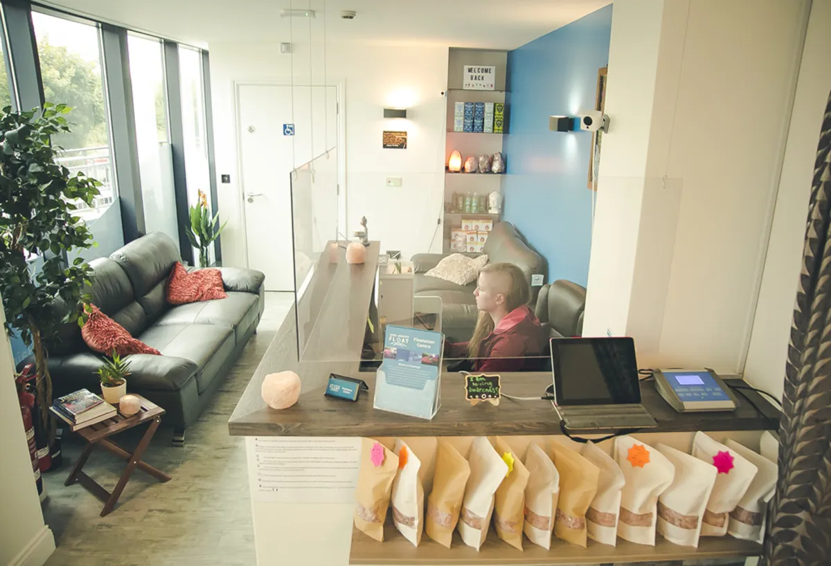 Reception area with seating and a person at the desk.