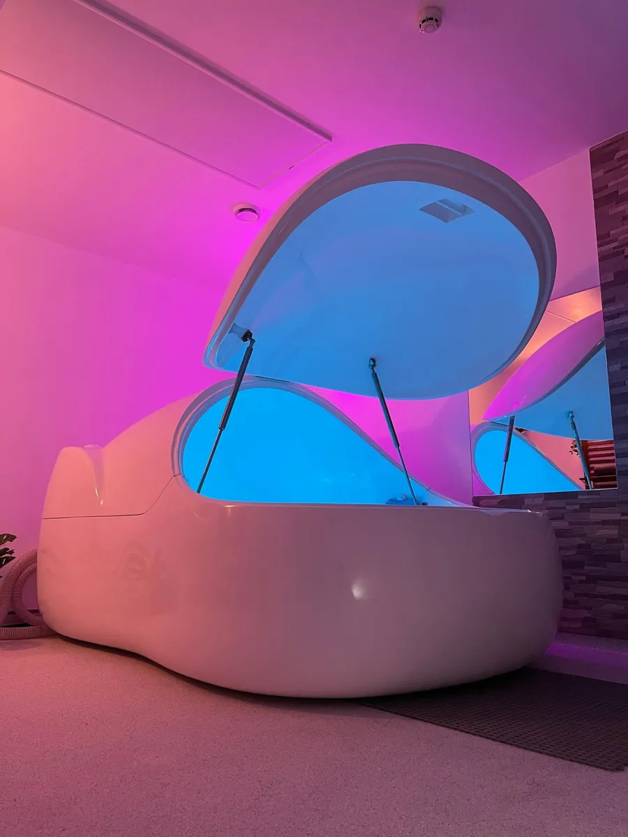 Open sensory deprivation tank with blue and pink lighting