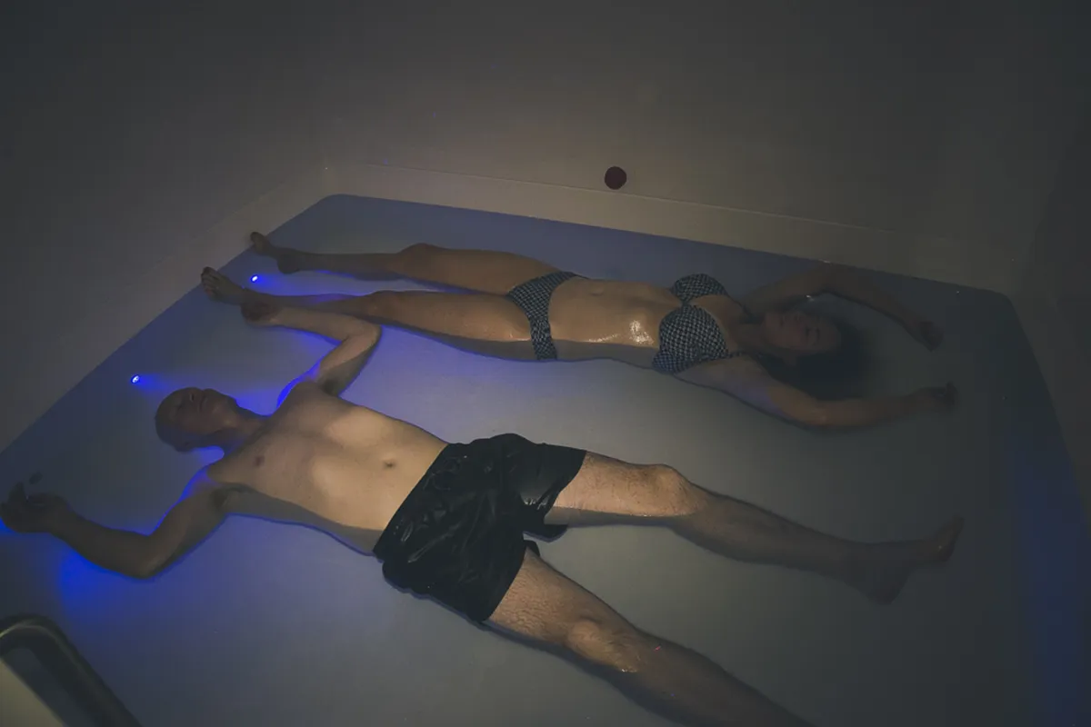 Two people floating in a dark pool.