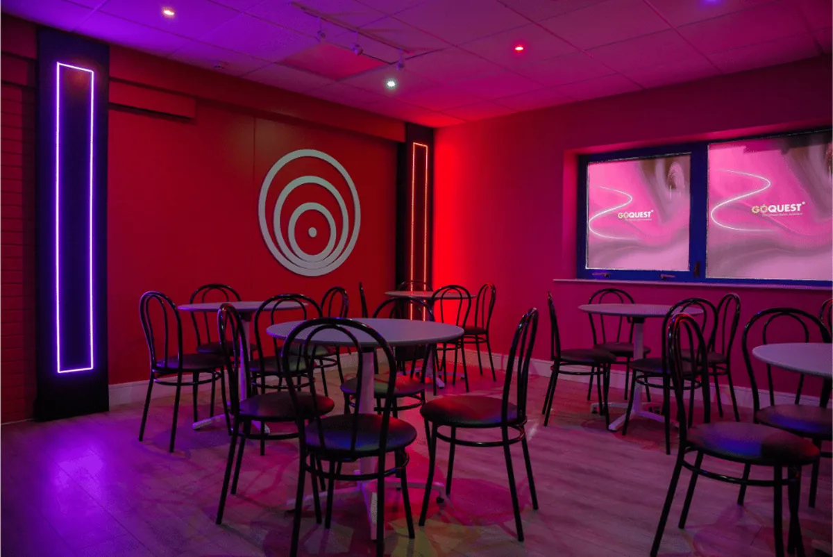 Empty room with round tables and chairs, neon lights.