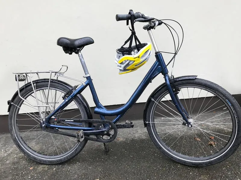 Blue bicycle with a yellow helmet on handlebars.