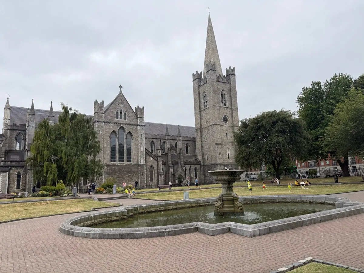 Stone cathedral with tall spire and garden fountain