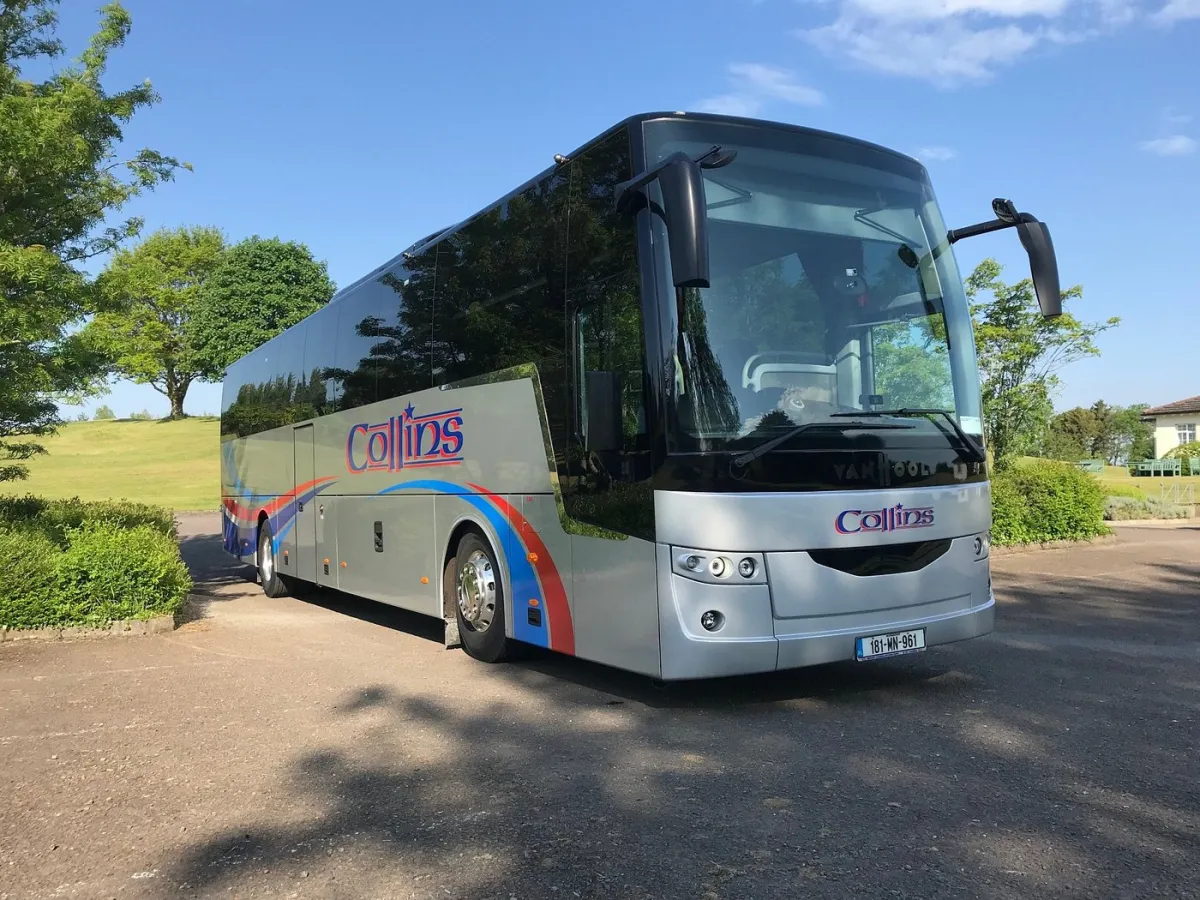 Silver tour bus parked on a sunny day