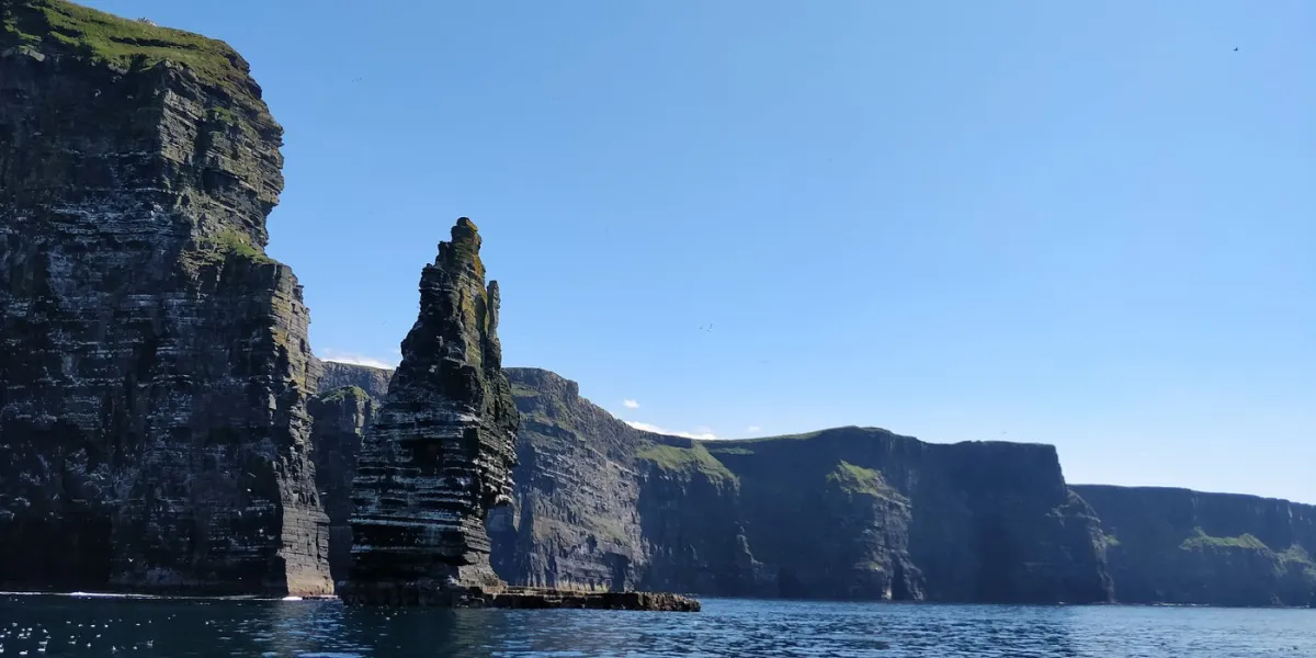 Cliffs and sea stack under clear blue sky
