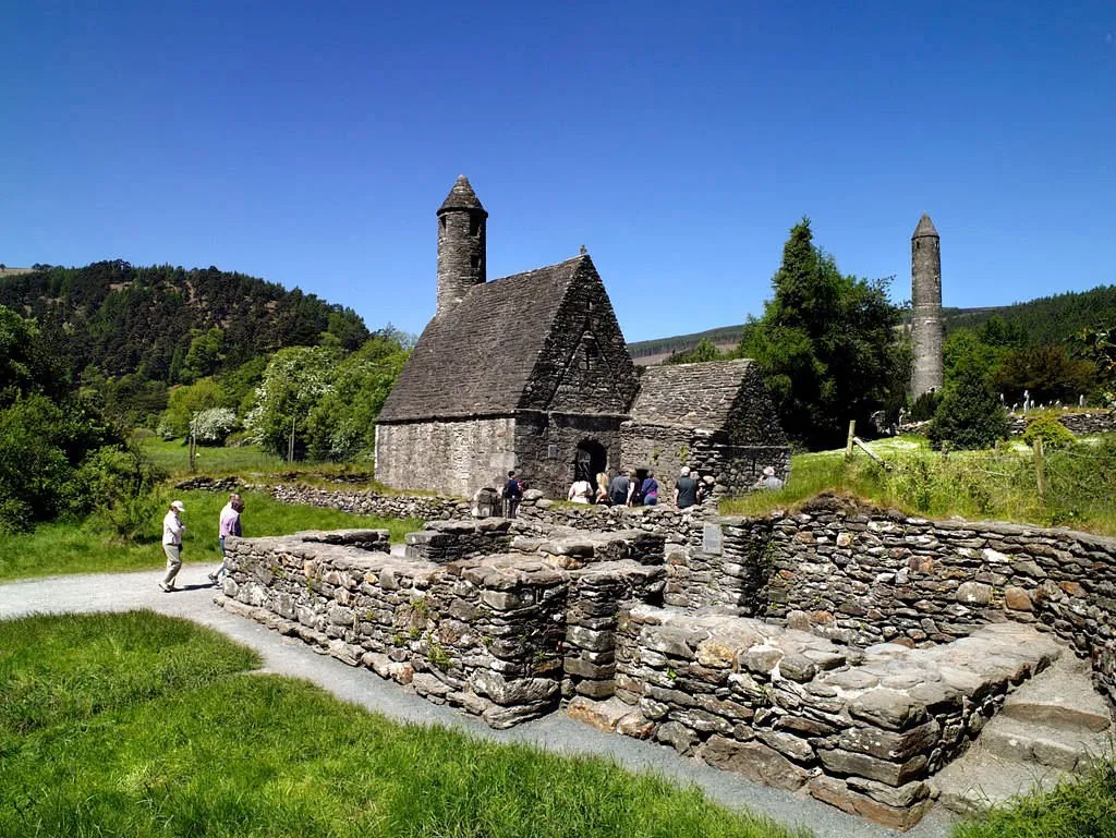 Ancient stone church and round tower in a green landscape.