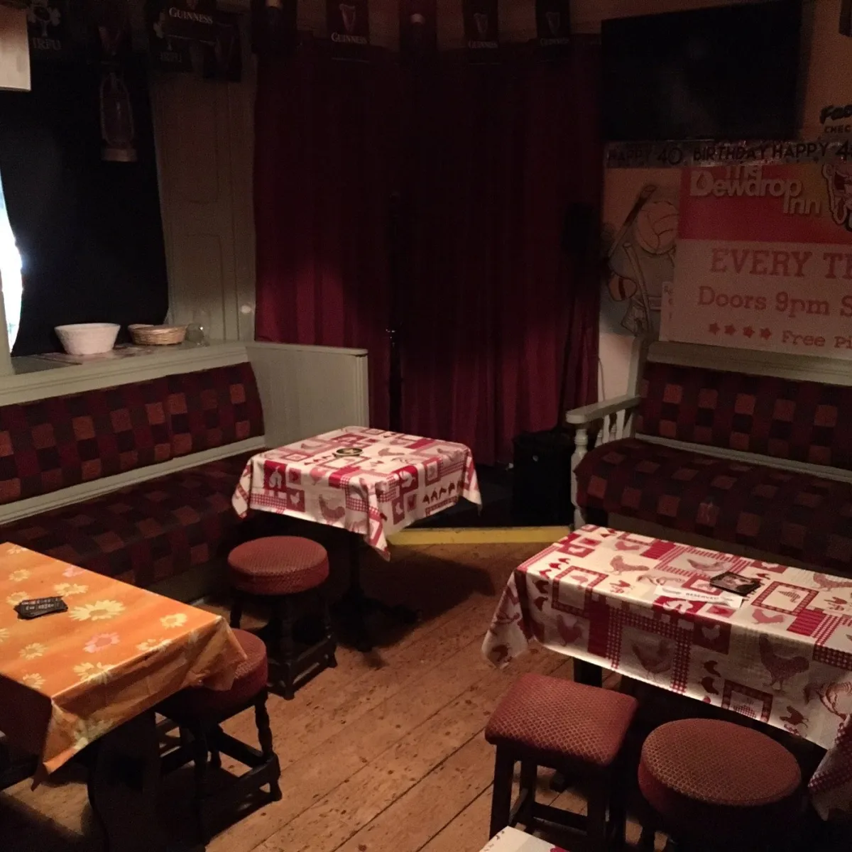 Cozy pub interior with tables and red curtains.