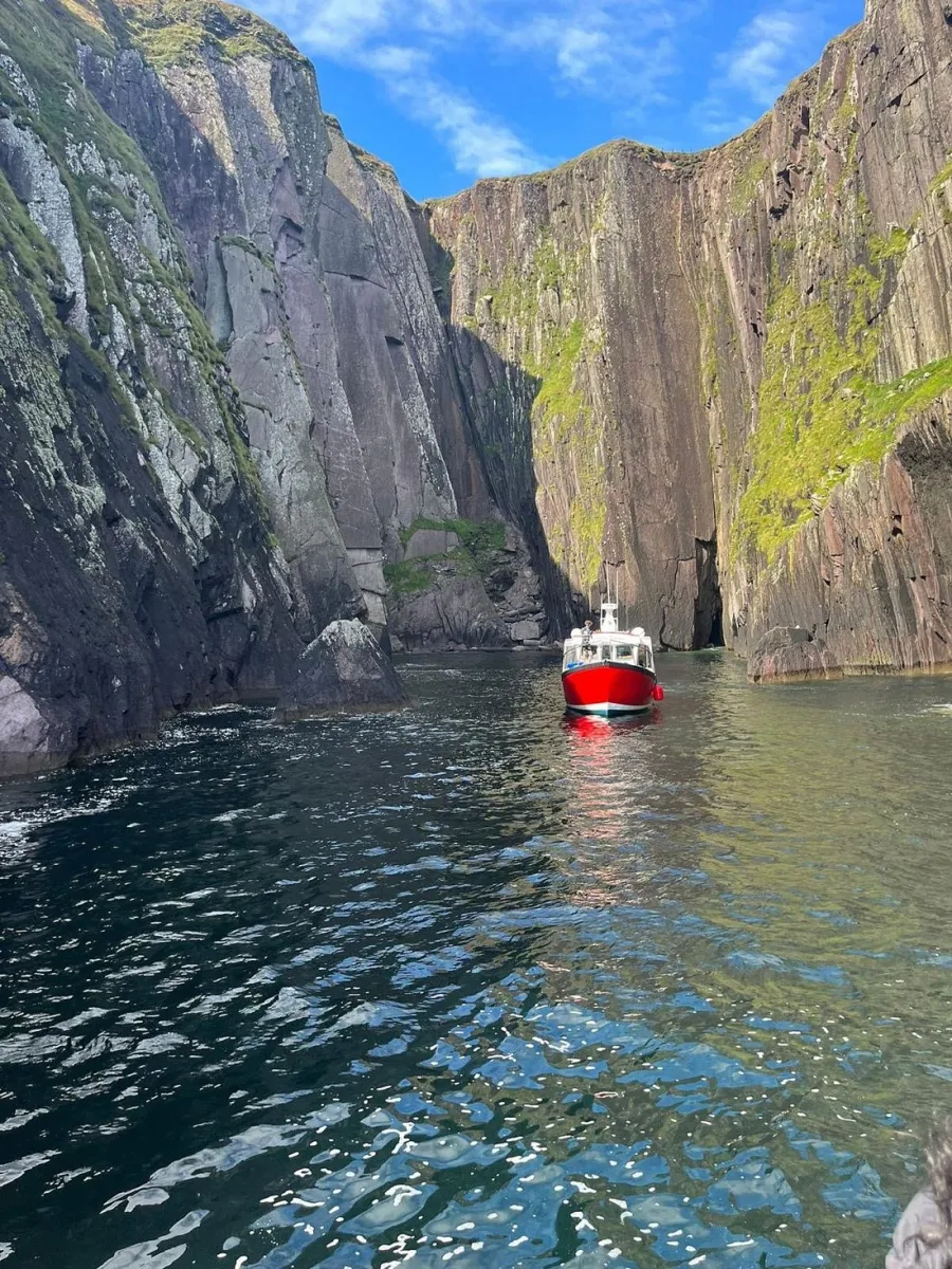 Red boat in a narrow cliff-lined waterway.