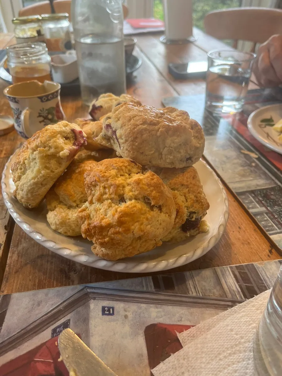 Plate of scones on a wooden table with drinks.
