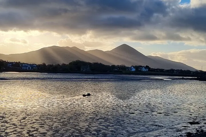 Sunset over mountains and water with clouds.