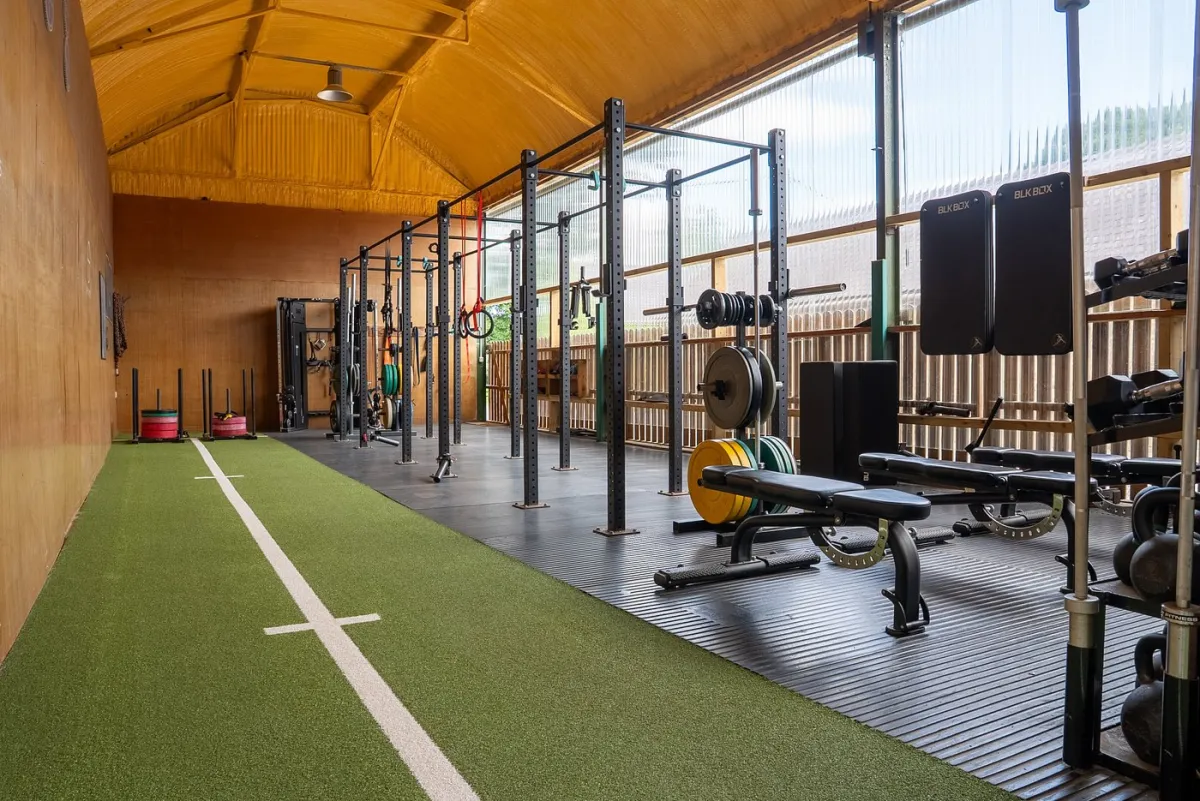 Interior of a gym with equipment and green turf.