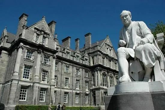 Statue in front of a historic stone building.