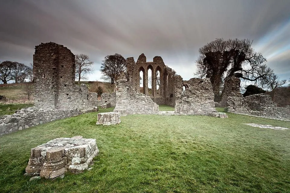 Ruins of an ancient stone building on a grassy field.