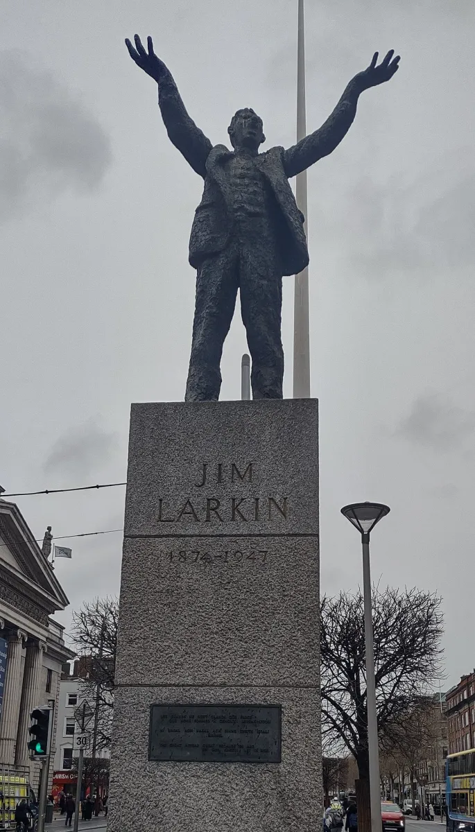 Statue of a man with arms raised on a pedestal.