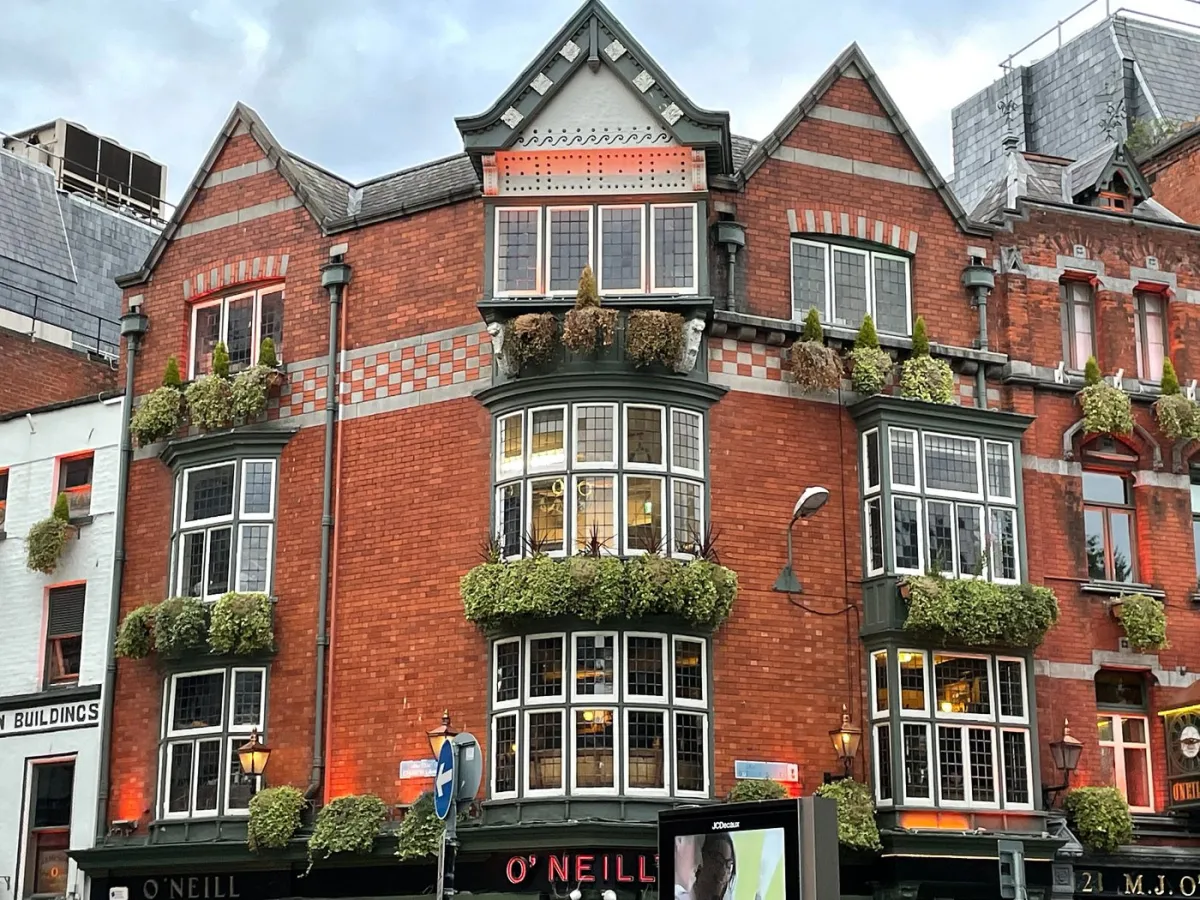 Historic red brick building with bay windows and greenery.