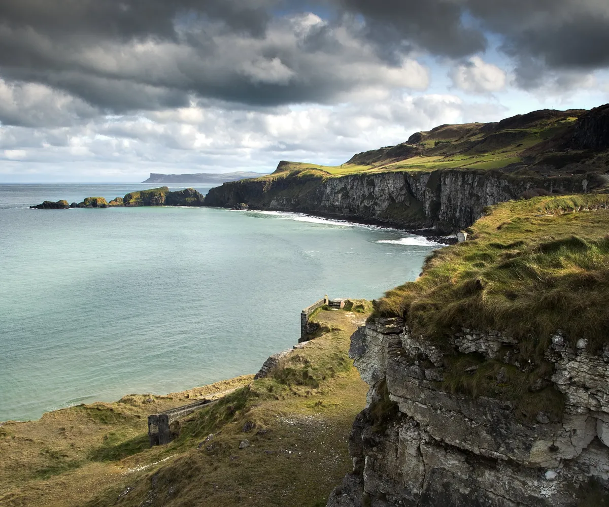 Coastal cliffs and ocean under cloudy sky