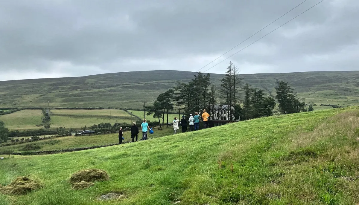 Group of people on a grassy hill with cloudy sky