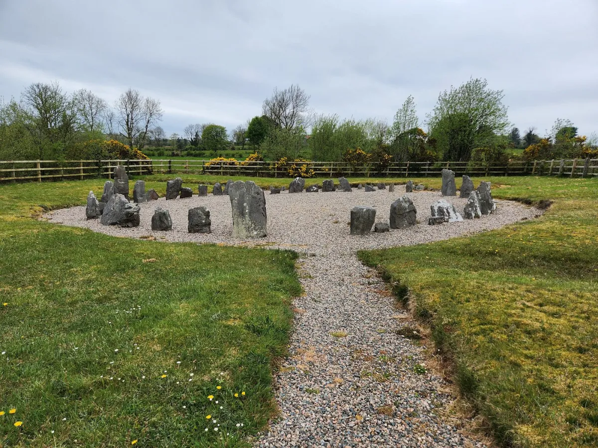 Stone circle in a grassy field with a gravel path.