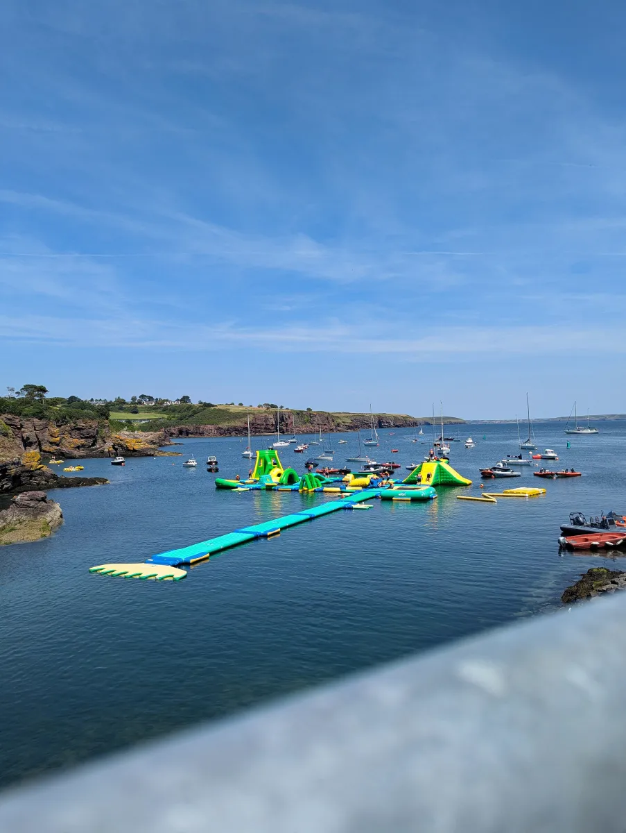 Floating inflatable water park in a bay with boats.
