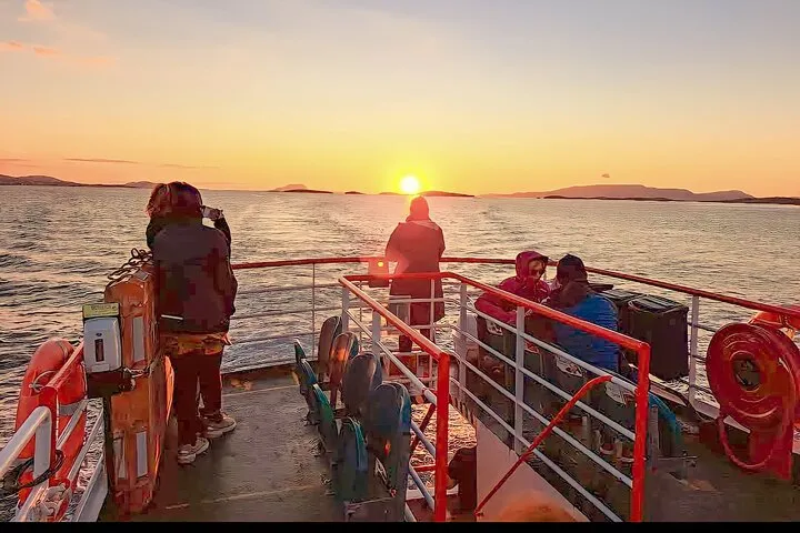 People on a boat watching the sunset over the ocean.
