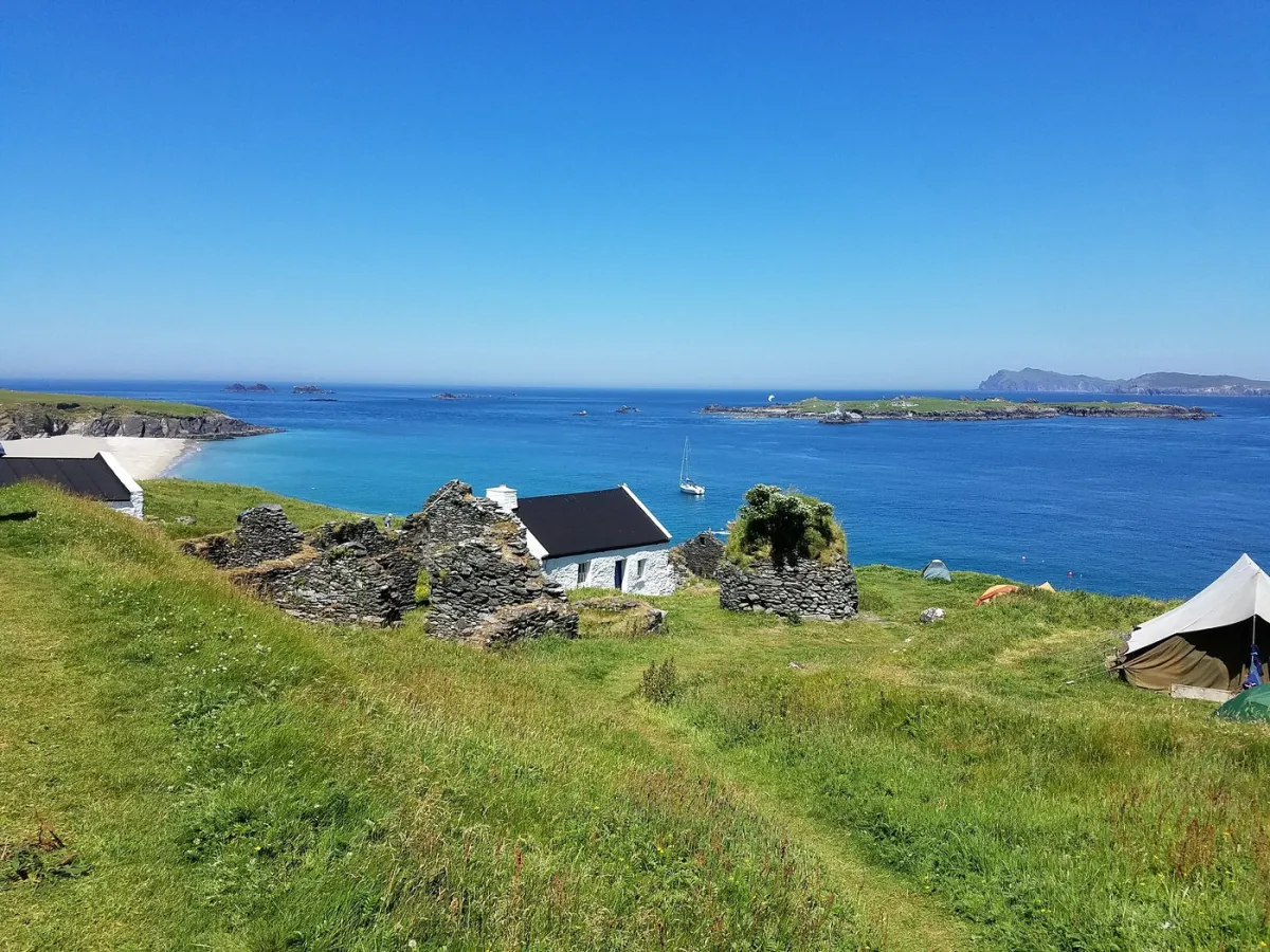 Coastal landscape with ruins and tents by the sea.
