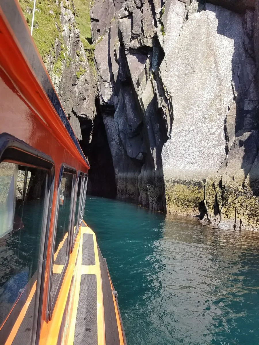 Boat entering a rocky cave on clear blue water