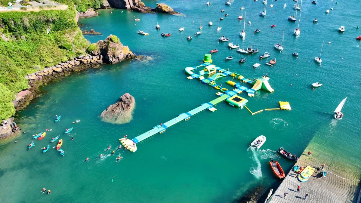 Aerial view of a floating water park and boats in a bay.
