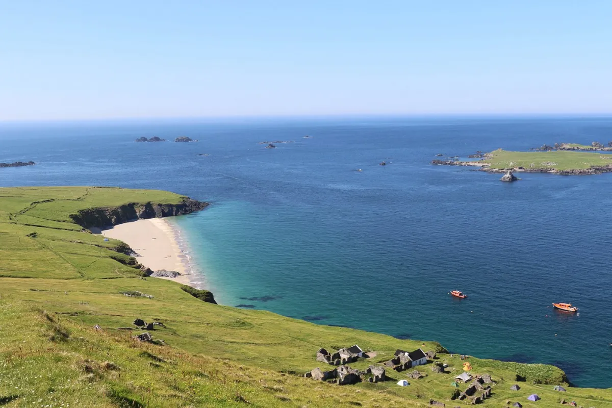 Coastal landscape with green cliffs and blue sea.