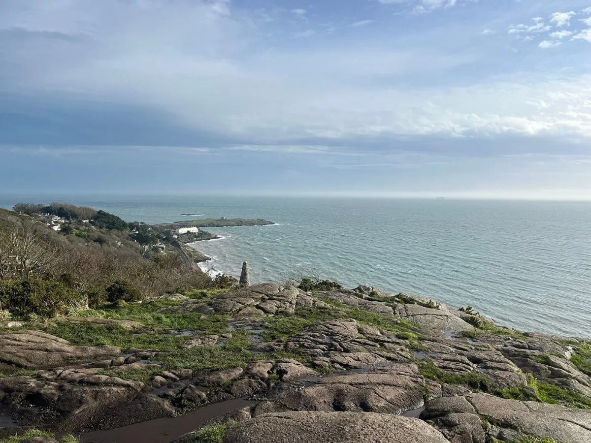Coastal landscape with rocky foreground and ocean view.