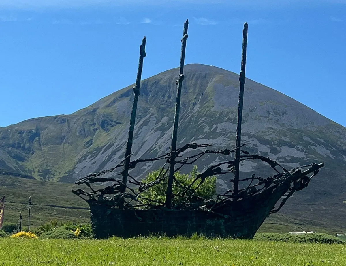 Metal sculpture of a ship with mountain backdrop