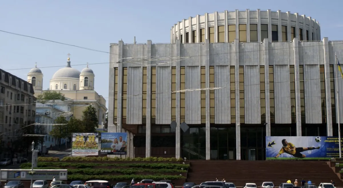 Будівля з колонами на передньому плані, церква на задньому