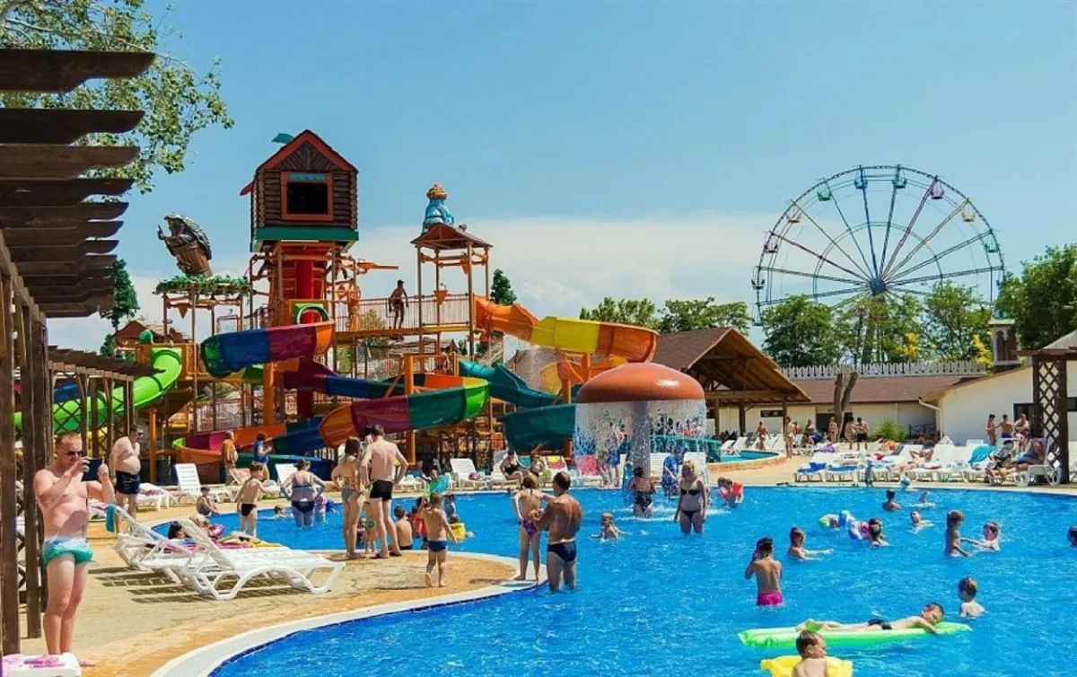 Люди відпочивають у басейні з водними гірками.