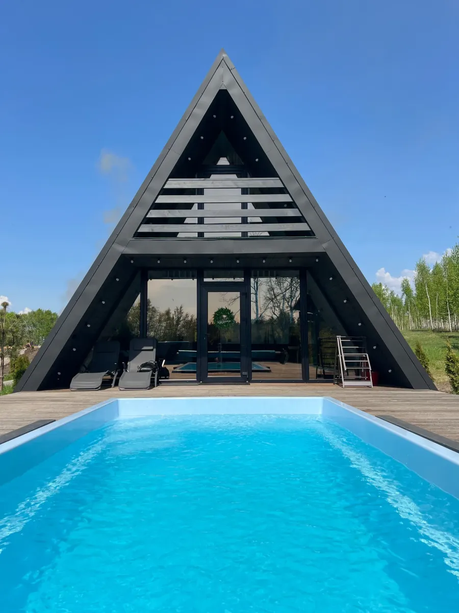 Великий блакитний басейн на тлі сучасного A-Frame будиночка в Sokolyni Gory.