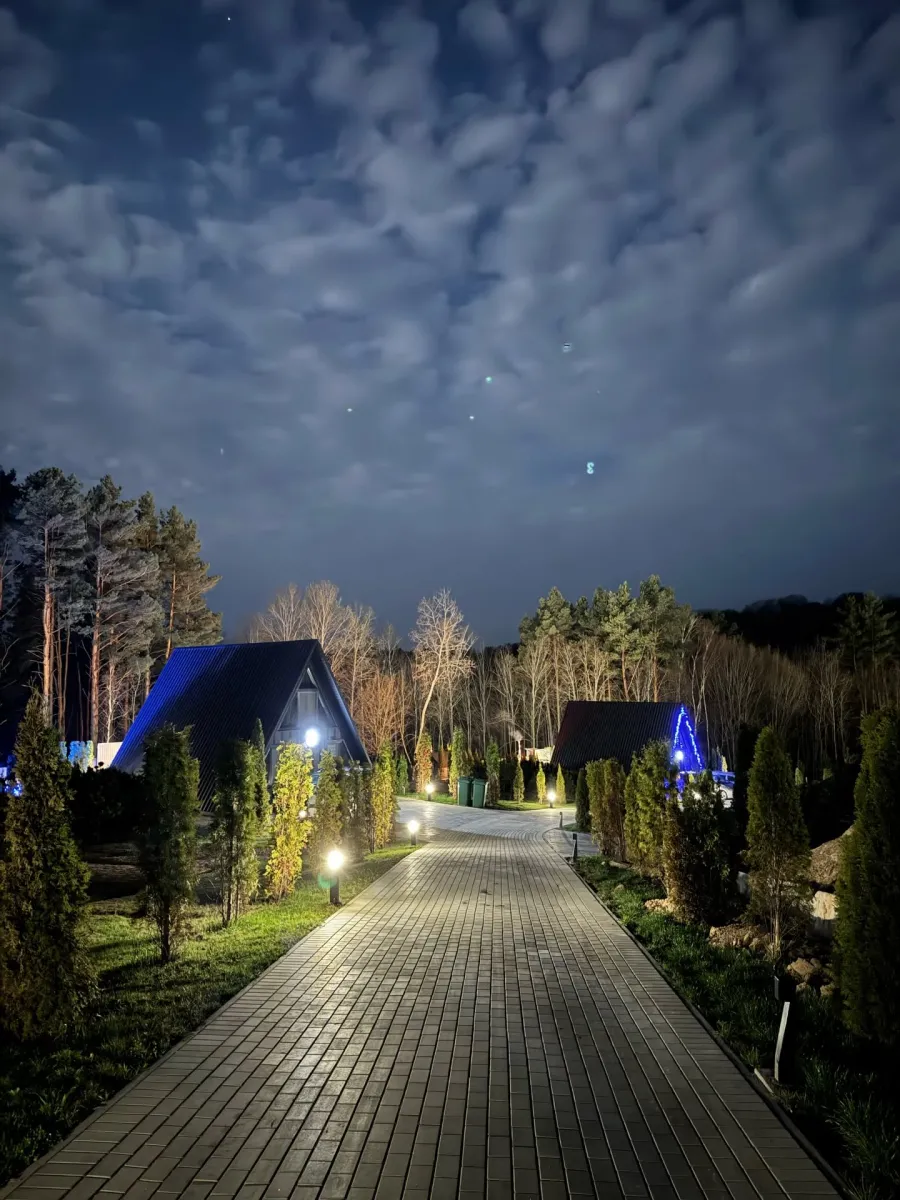 Вечірнє освітлення доріжок і A-Frame будиночків під зоряним небом у Sokolyni Gory.