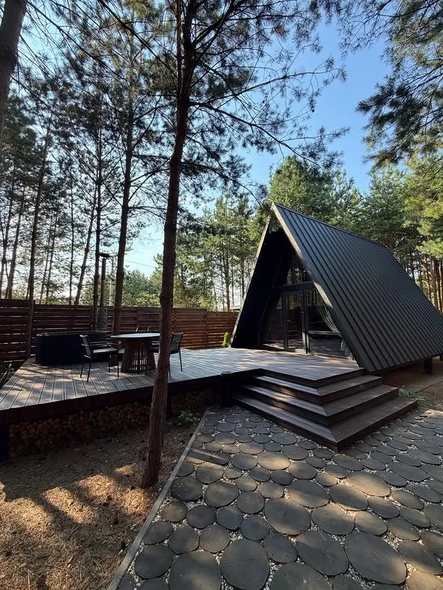 Трикутний котедж A-Frame, літня тераса та оригінальна садова доріжка з круглих дерев'яних спилів у комплексі Grand Forest Лісопіль.