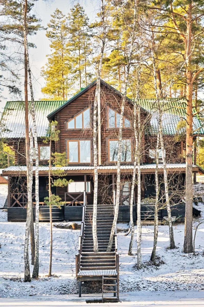 Дерев'яний котедж SPA Chalet зі сходами, що ведуть до засніженого берега та озера на курорті Zaliv.