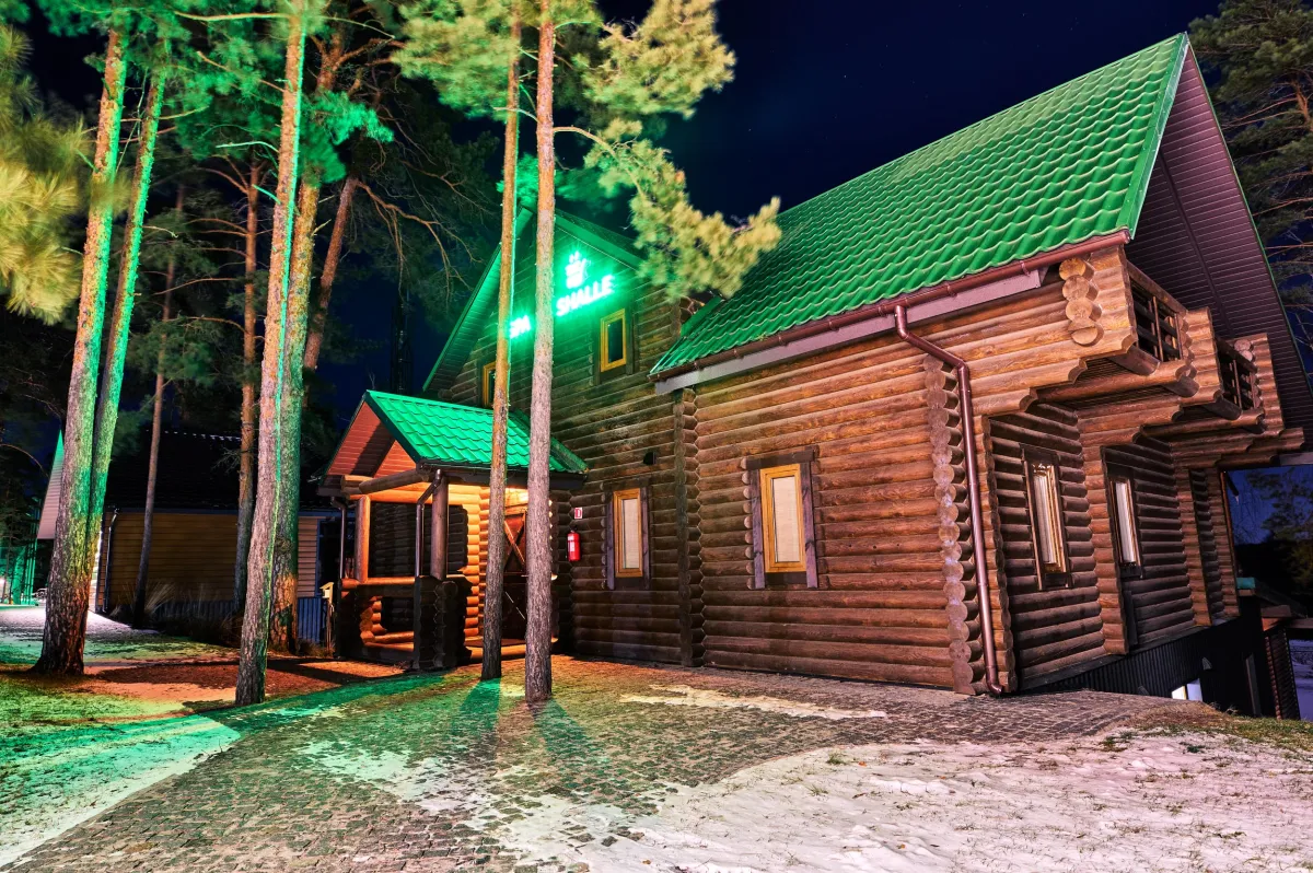 Вечірній вигляд дерев'яного зрубу комплексу SPA Chalet у зимовий час з освітленням на курорті Zaliv.