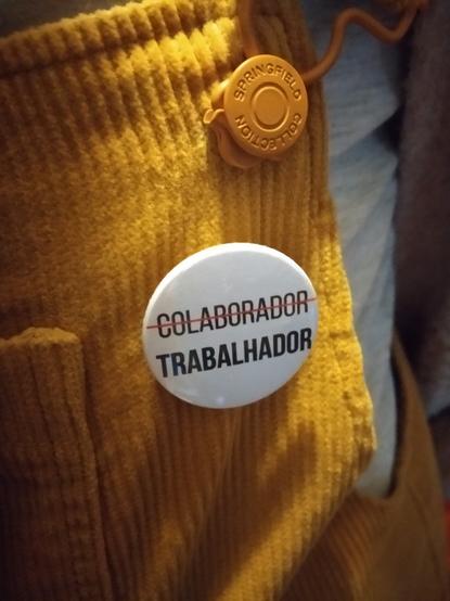 Crachá com o vocábulo "colaborador" riscado e o vocábulo "trabalhador" evidenciado como o correcto.