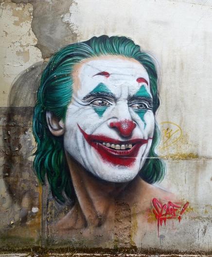 StreetArtWall. On a wall in a hall in Lorraine is sprayed / painted a mural of the fictional villain "Joker" from the comic series "The Batman". It is a clown with green hair and crazy look. The Joker was played by many actors and always had a special look. The actor of this Joker in the movie was Joaquin Phoenix and plays before
the transformation into the later villain. As a mentally ill "Arthur Fleck" (aka The Joker) in 2019, Phoenix played himself in a dark psychological thriller until the Oscar winner.
Oh, and it's carnival in Germany.