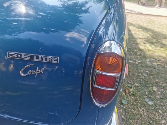 Rear right hand corner of a dark blue Rover P5B Coupe.  A 3.5 litre badge is situated on the back of the boot/trunk lid above the word Coupe in chrome script.