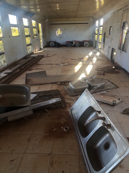 Inside the carriage with abandoned sinks and other rubbish. Some sunlight beams stream onto the floor