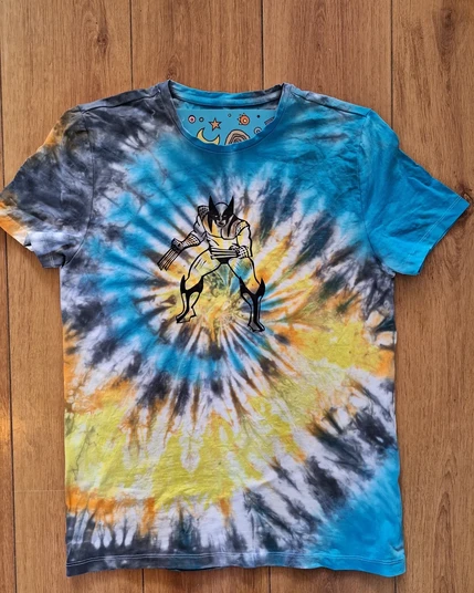 A tie dyed shirt in blue,yellow and black in a swirl. On the chest area is a linoprint of Wolverine