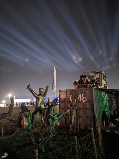Container mit Schrottauto darauf, davor Skulpturen