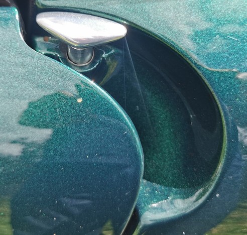 A detail of a metallic green car.