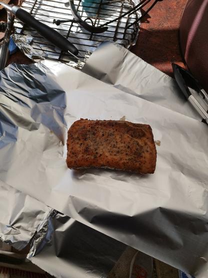 A piece of pork sitting on aluminium foil about to get wrapped